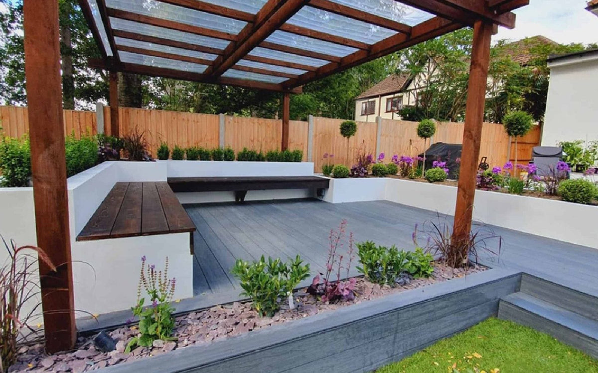 Artificial decking beneath a garden pergola, featuring composite boards.