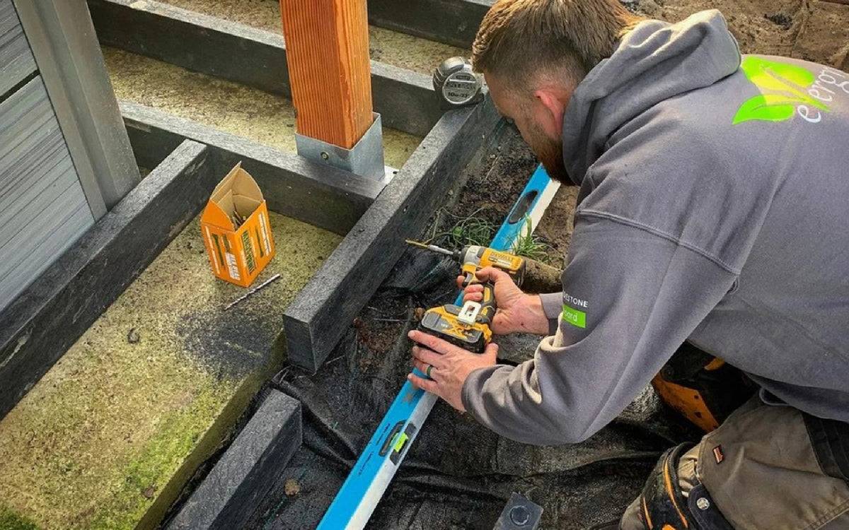 Installer fitting recycled plastic artificial lumber posts and joists for a decking subframe.