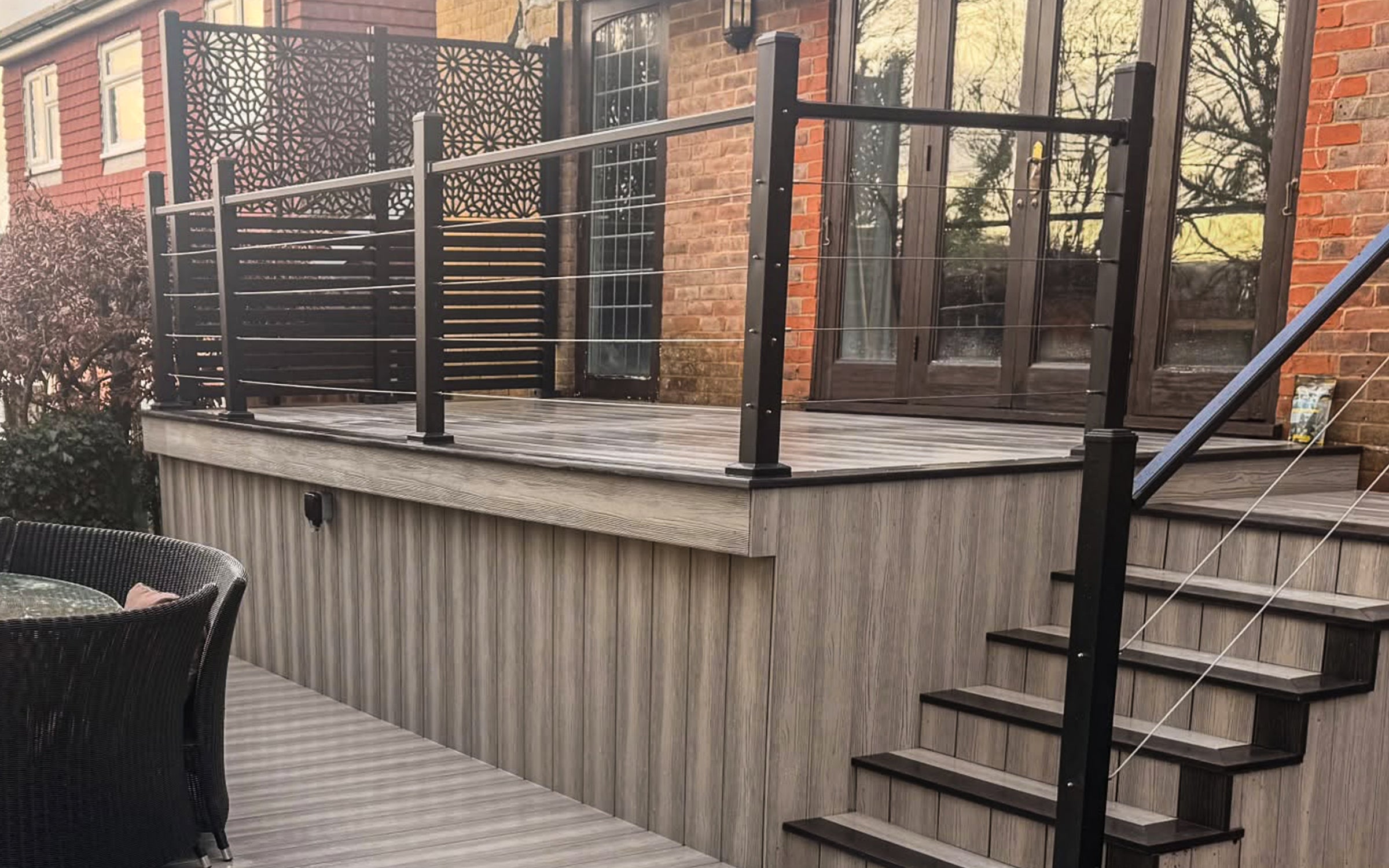 composite deck with black metal railing and stairs leading to a house