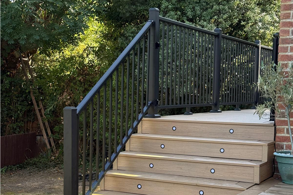 composite steps leading to a deck with metal railing, surrounded by greenery