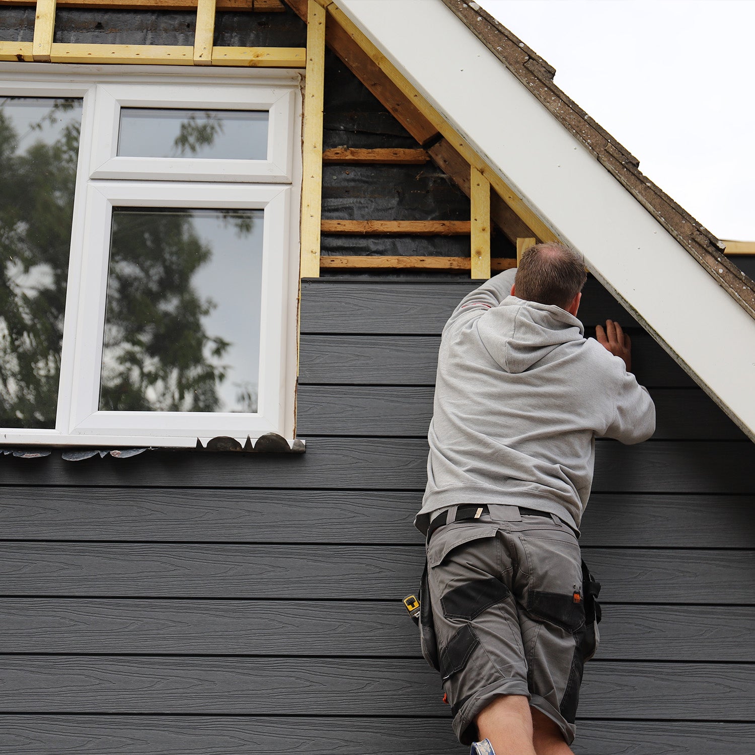 NeoTimber® approved installer fitting grey deluxe woodgrain composite cladding onto the front of a house exterior