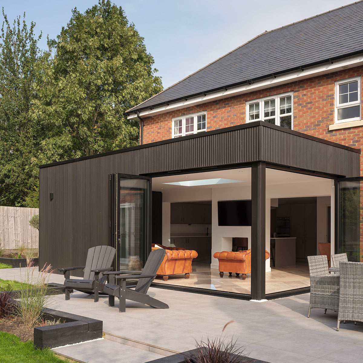 modern patio extension using composite cladding with furniture in a garden setting