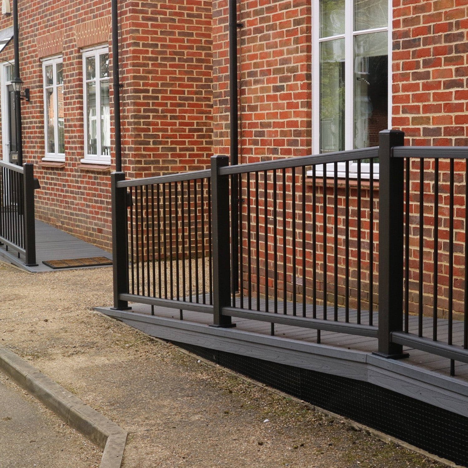 black composite ramp and railings leading up to a brick building with windows