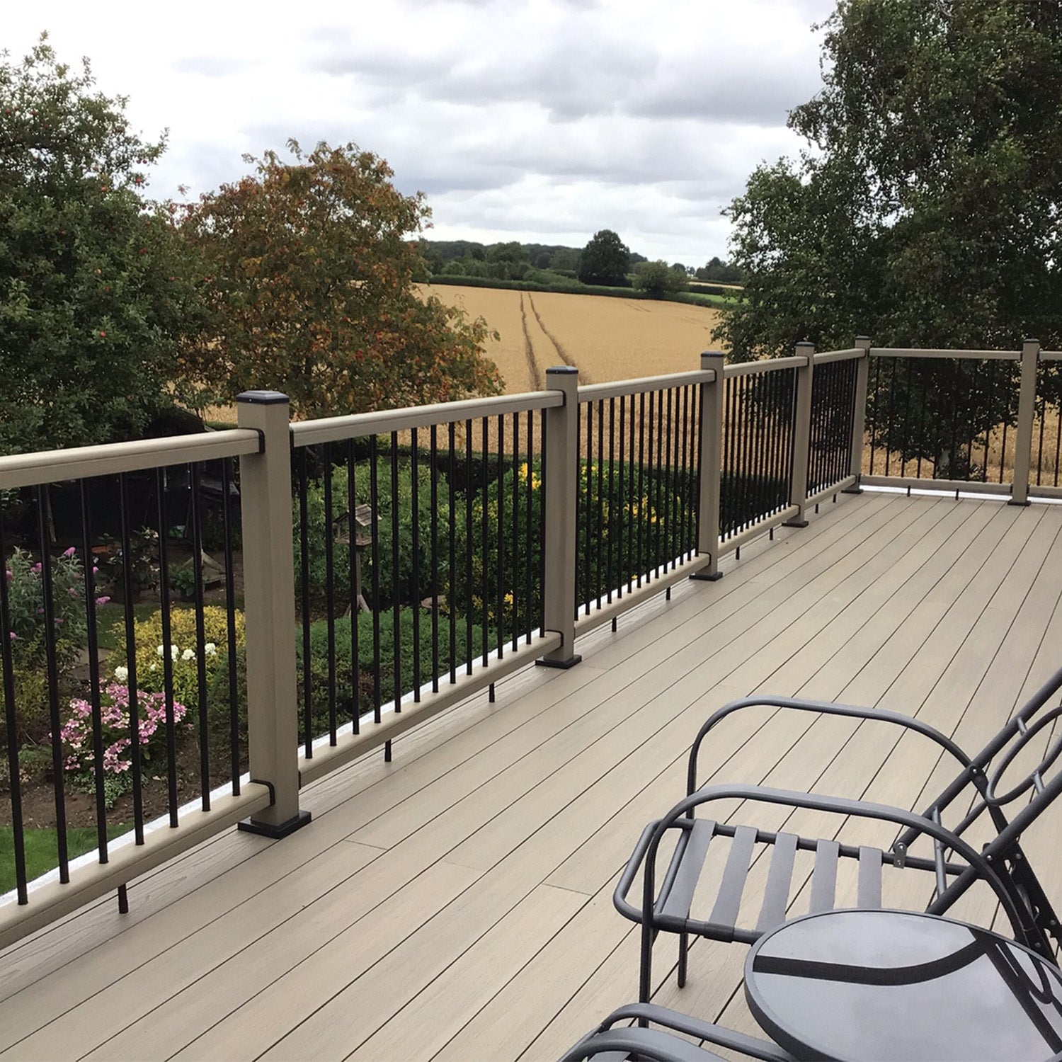 composite deck with railing overlooking a scenic landscape with trees and fields