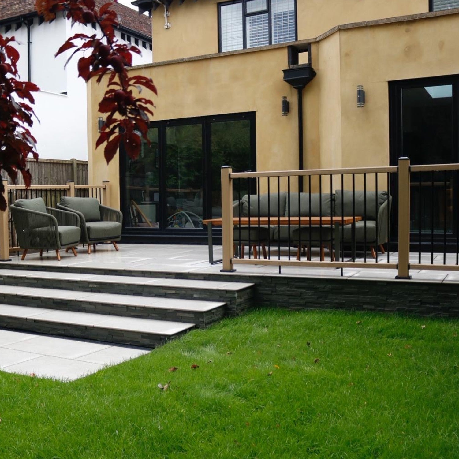 backyard patio with outdoor furniture, composite balustrade, garden steps and lawn leading to a modern home