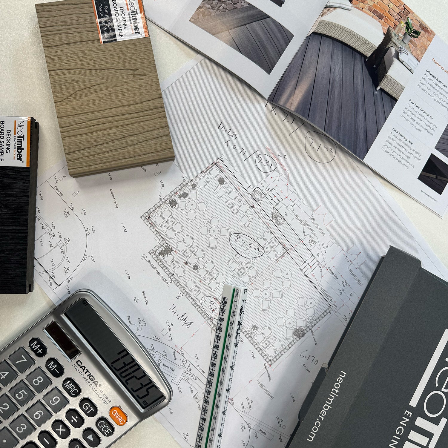 neotimber blueprints with a calculator, ruler, and architectural model on a desk