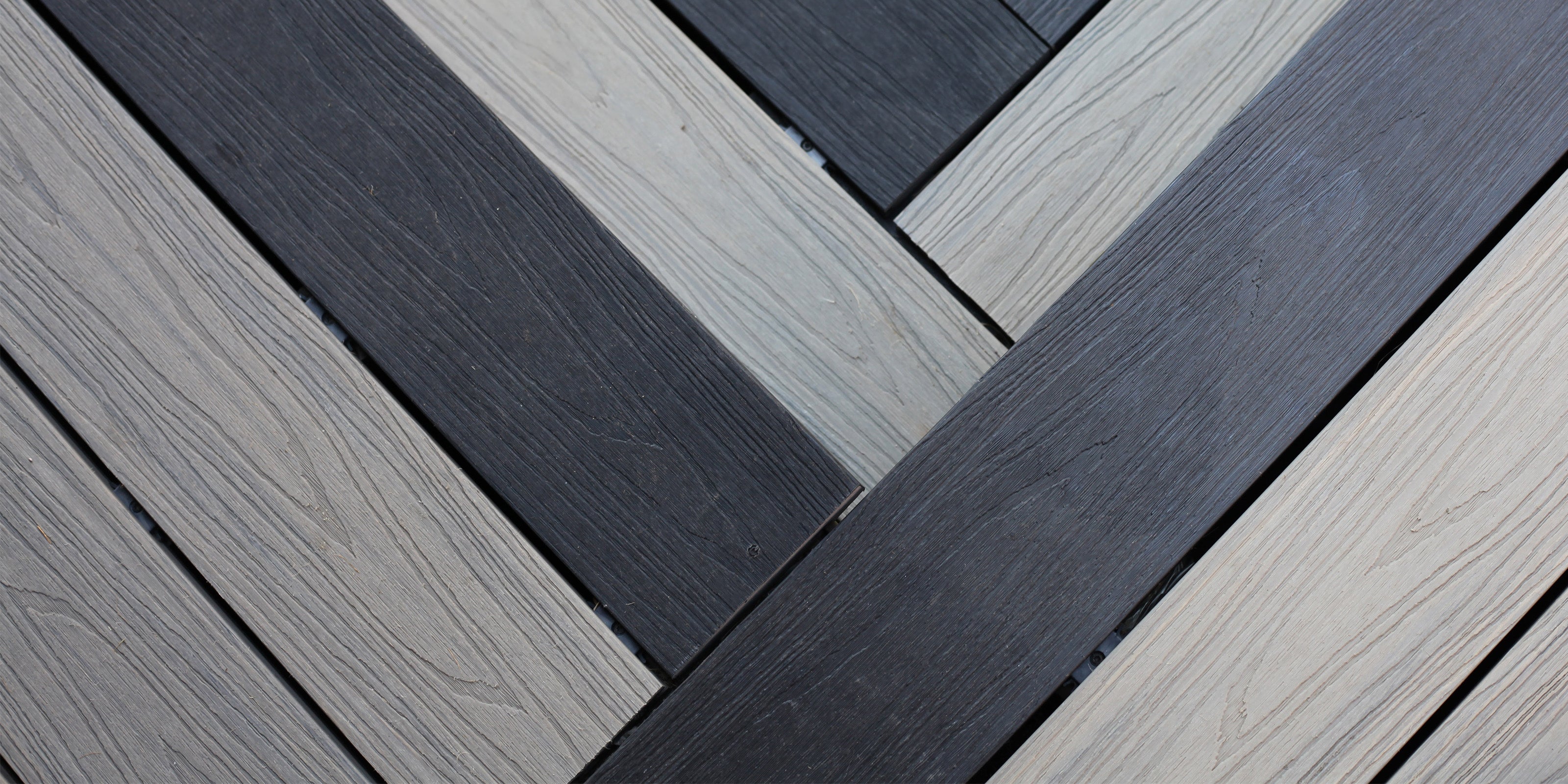 close-up of neotimber light grey and dark black composite deck planks arranged in a herringbone pattern