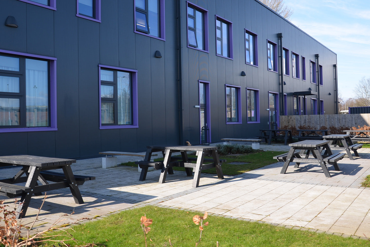 Modern building exterior with purple-framed windows and NeoTimber recycled plastic picnic benches