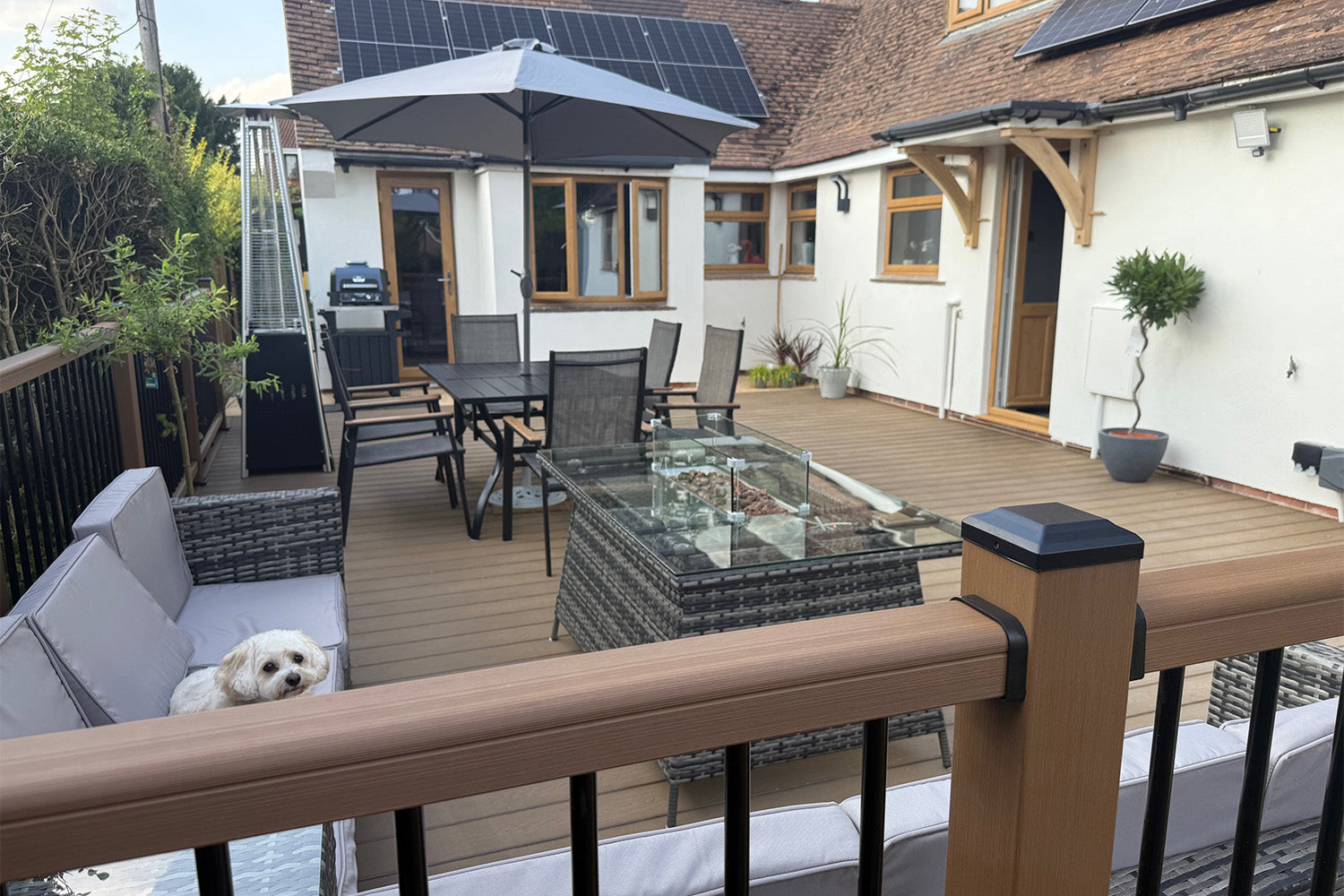outdoor patio area with furniture, parasol, and a dog on a composite deck enclosed by composite balustrades