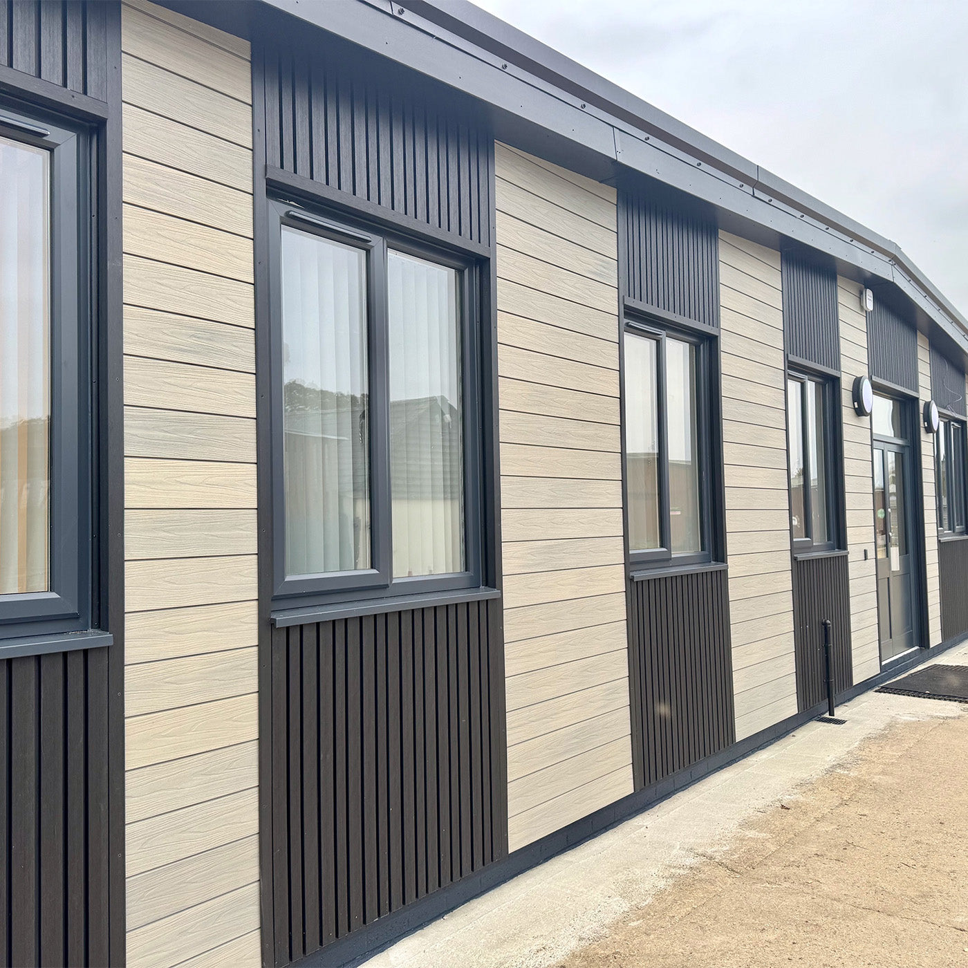 modular building with beige composite siding and black window frames