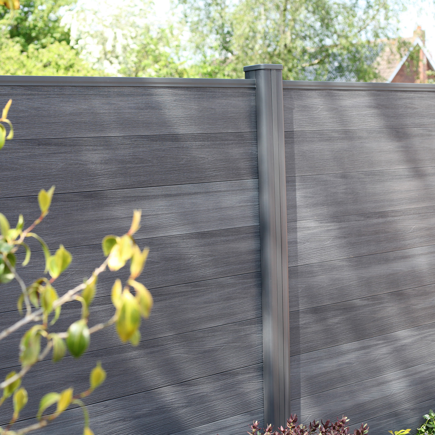 grey composite fencing panels with landscaped greenery in the foreground