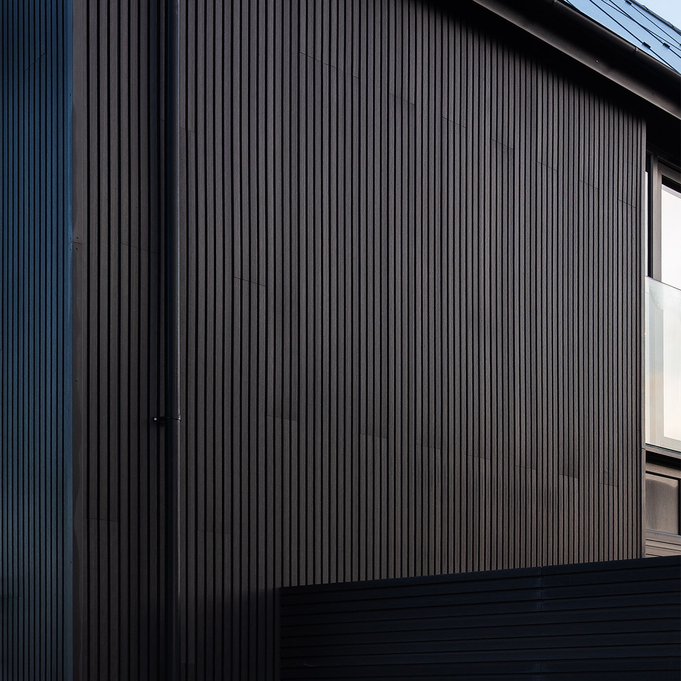 modern building exterior featuring dark slatted composite cladding panels