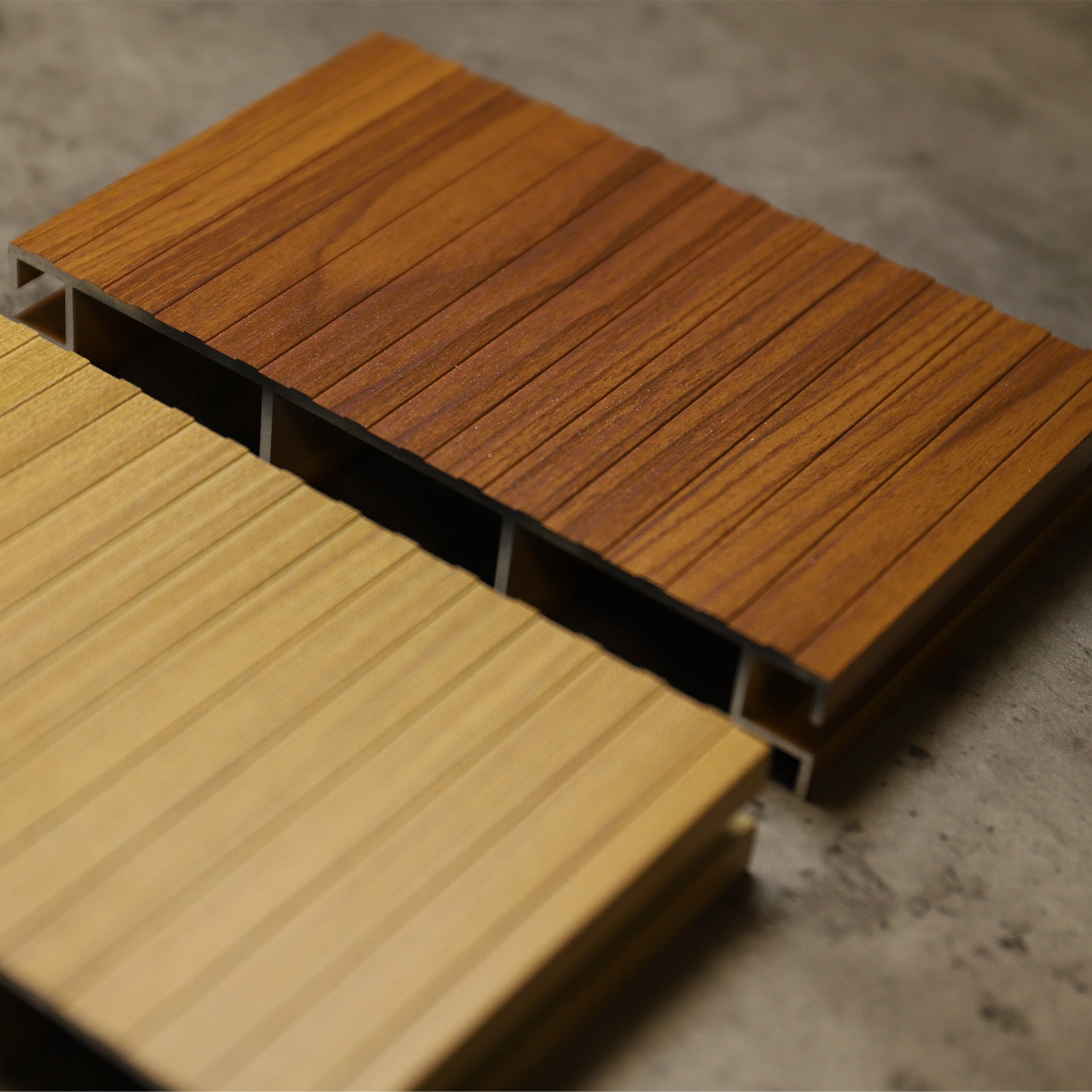 two aluminium deck samples, one brown and one beige, on a concrete floor