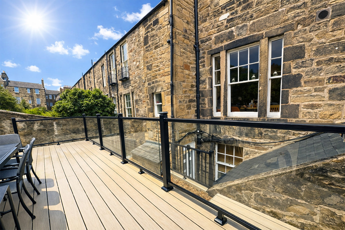 outdoor deck with neotimber glass railings and stone building in the background