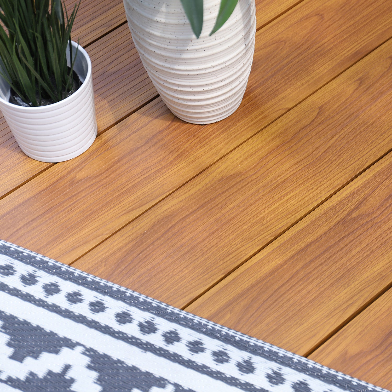 aluminium deck boards with two potted plants and a patterned rug