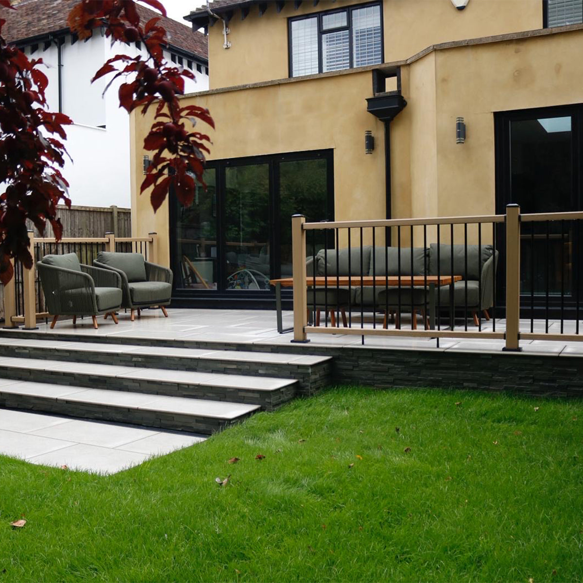 backyard with composite balustrades, patio furniture, steps leading to a house, and green grass