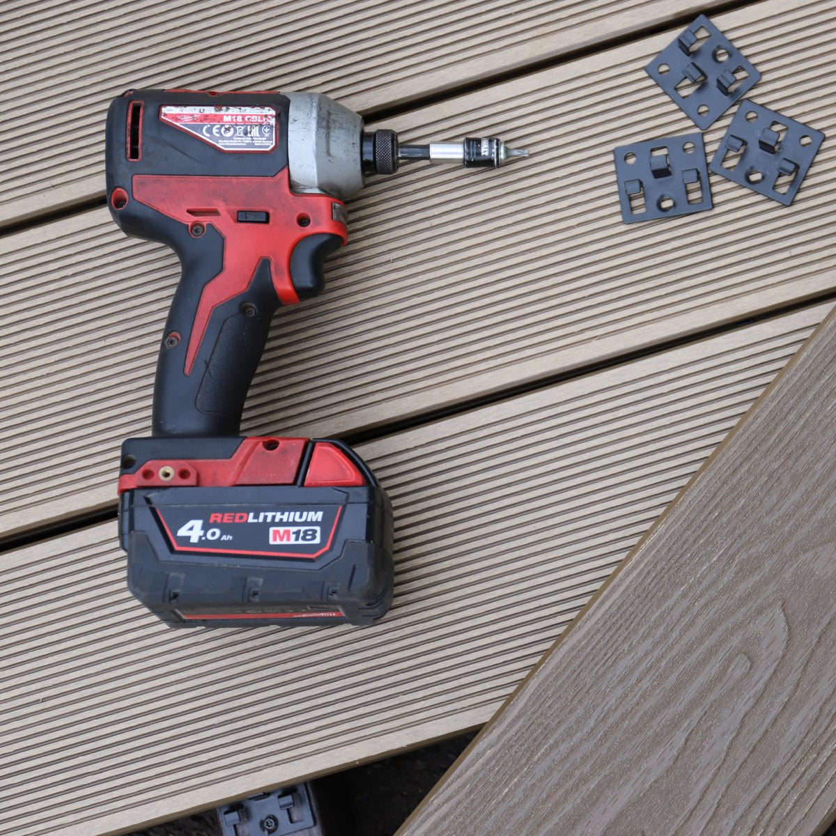 red and black cordless drill on a composite deck surface with a battery pack attached