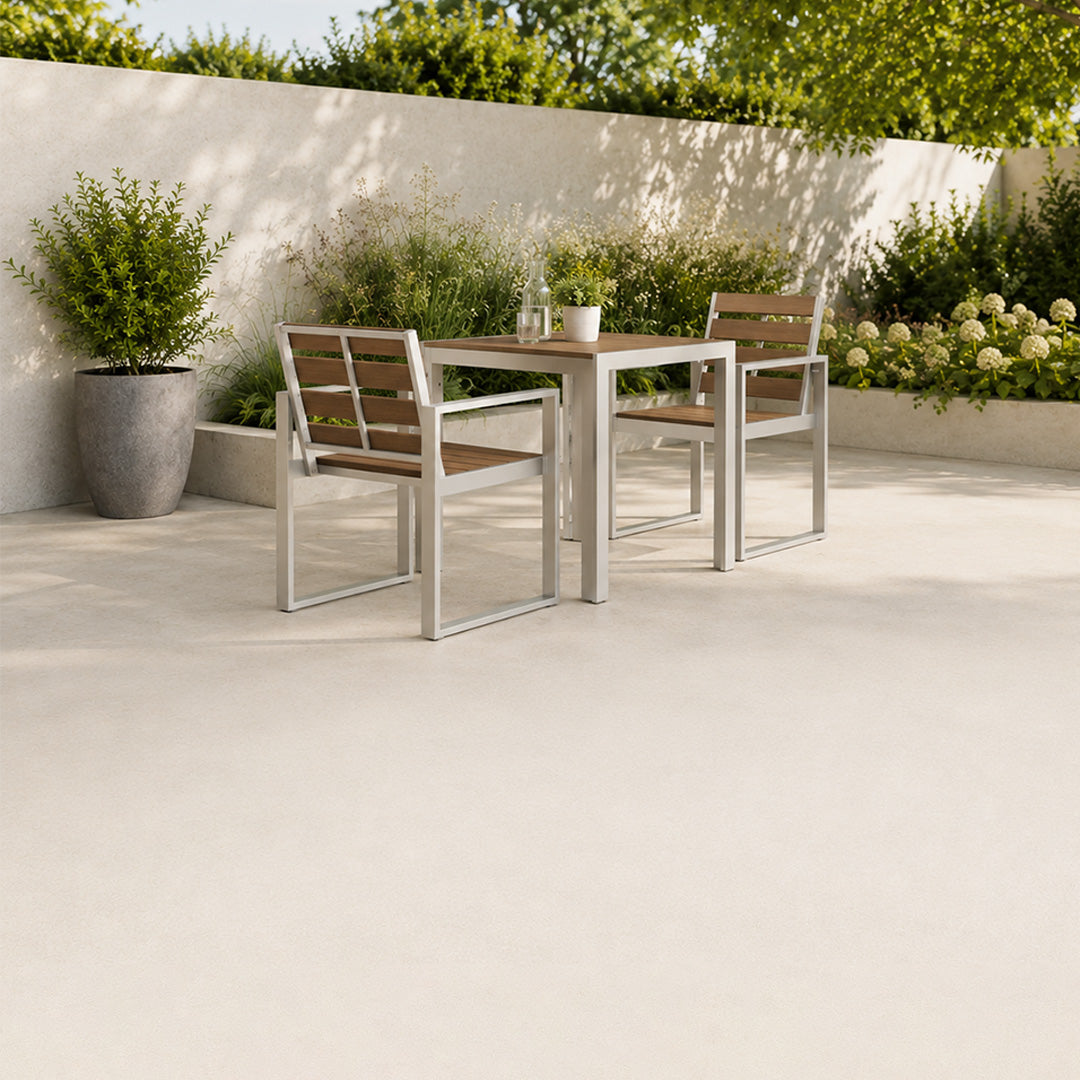 outdoor composite furniture patio set with table and chairs on a concrete patio with plants and flowers in the background