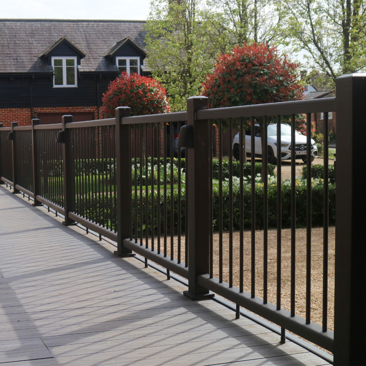 composite balustrade with metal spindles next to composite decking with house and car in background