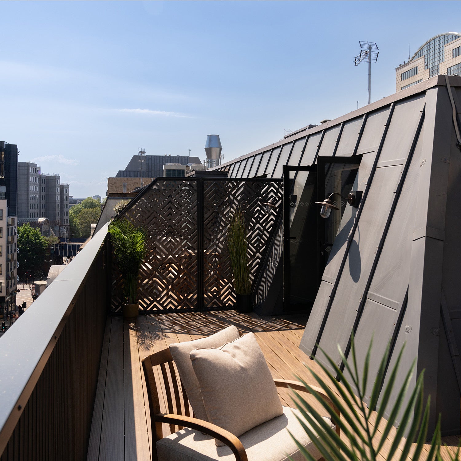 rooftop aluminium decking patio with wooden chair, cushions, decorative elements and city skyline