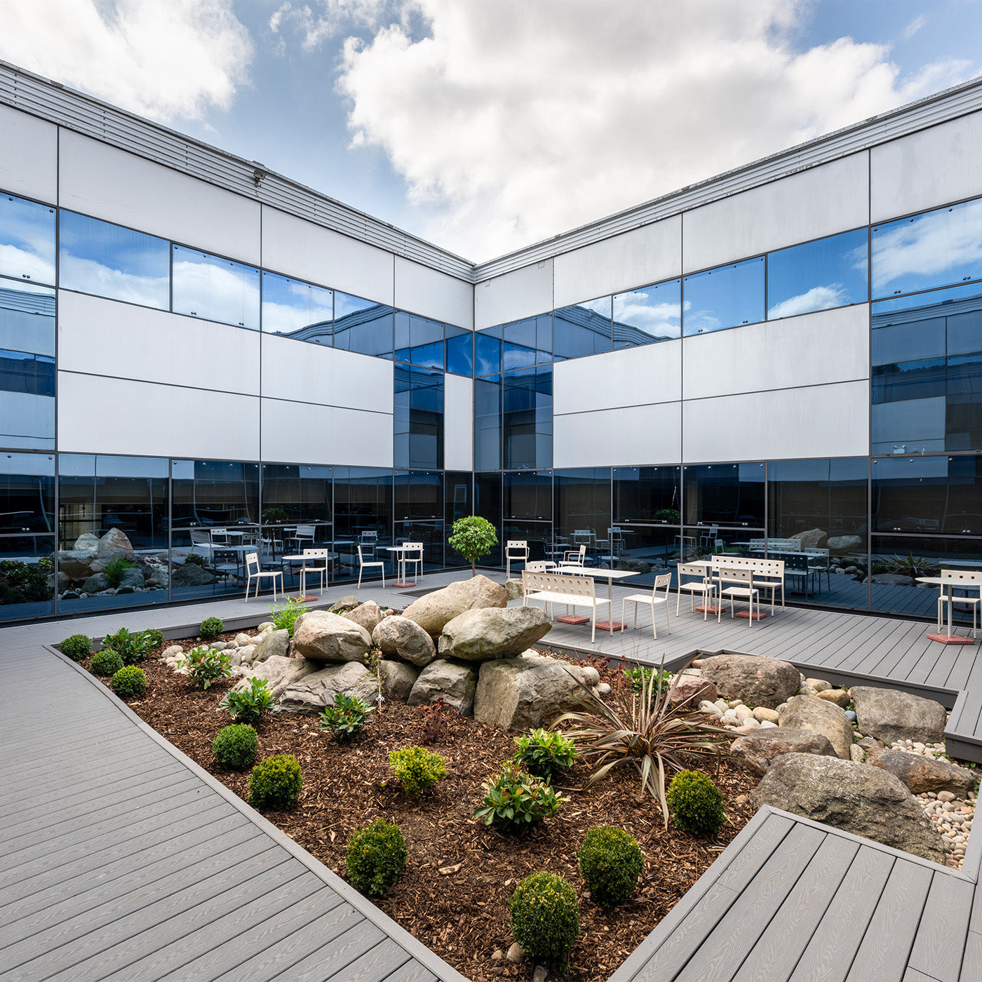 contemporary office courtyard featuring composite decking, landscaping and glass facades