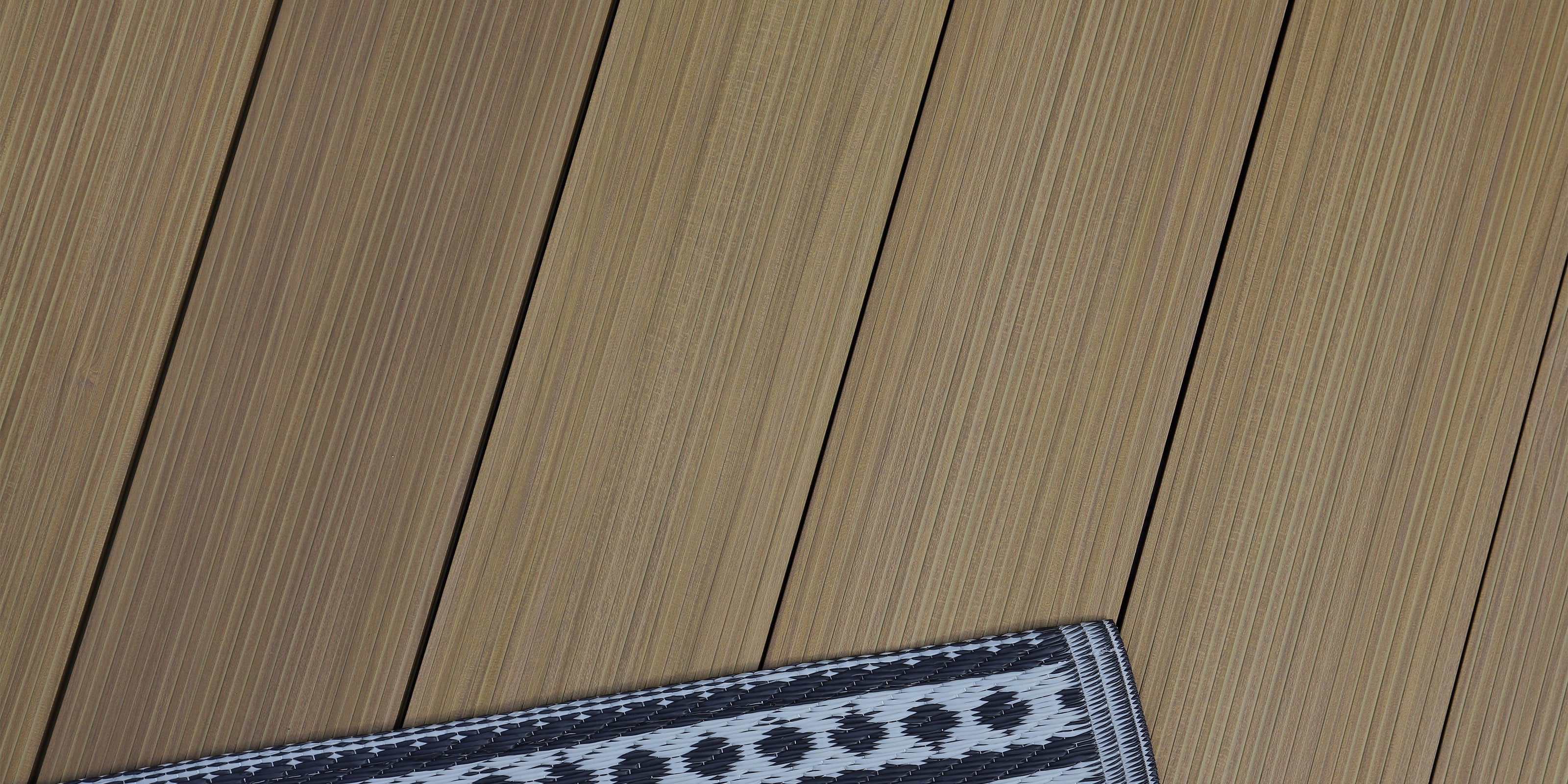 neotimber aluminium decking image gallery - close-up of an aluminium deck floor with a small rug featuring a geometric pattern
