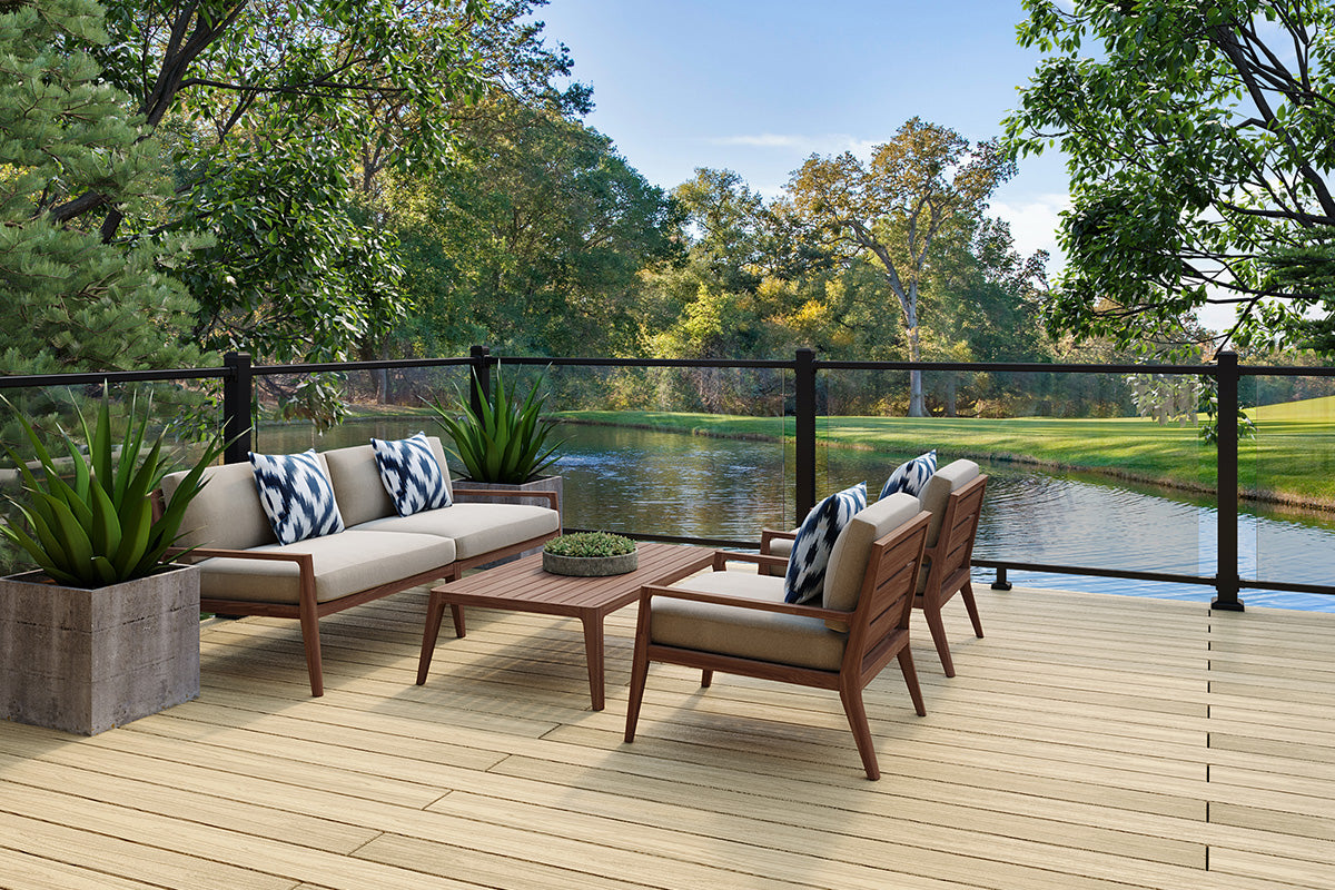 outdoor patio furniture set on a composite deck with glass balustrade overlooking water and woodland