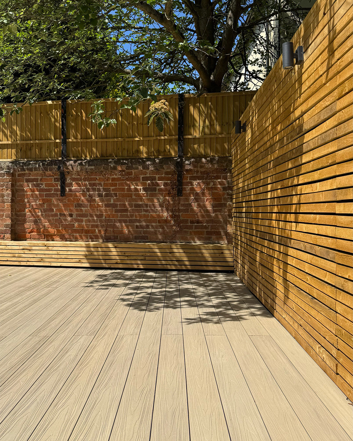 neotimber composite deck with a wooden fence and tree in the background