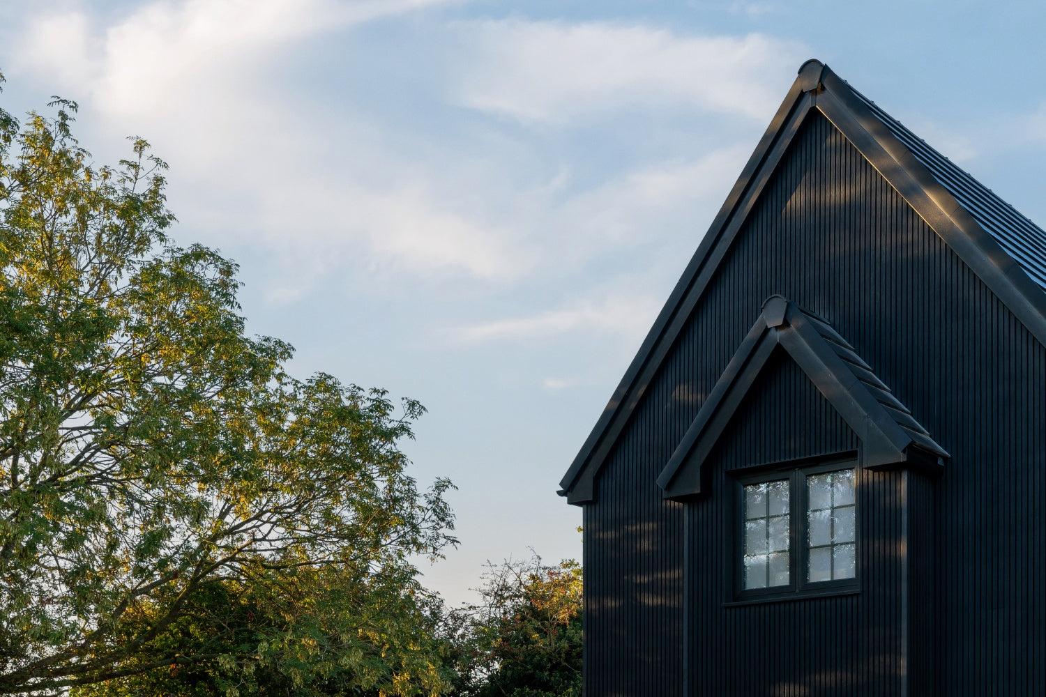 black composite cladded house with a gabled roof against a blue sky
