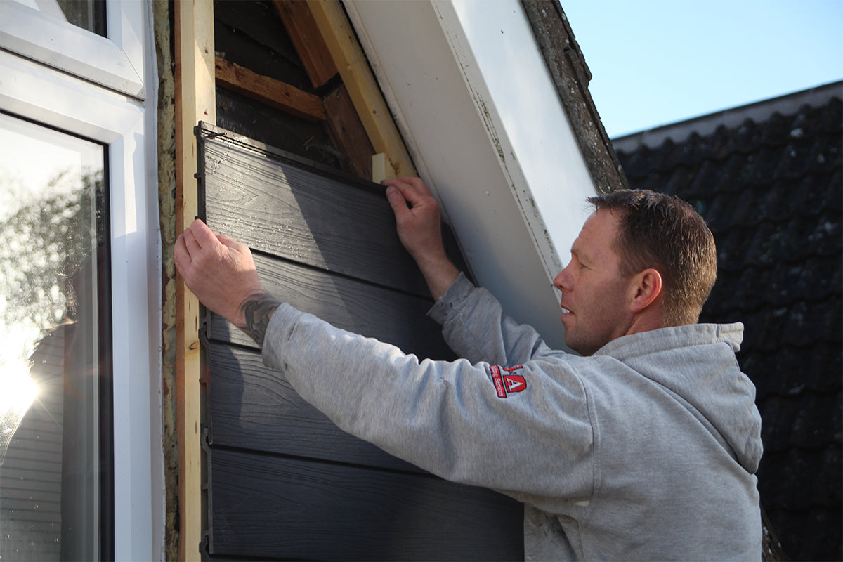 person installing composite cladding on a building exterior