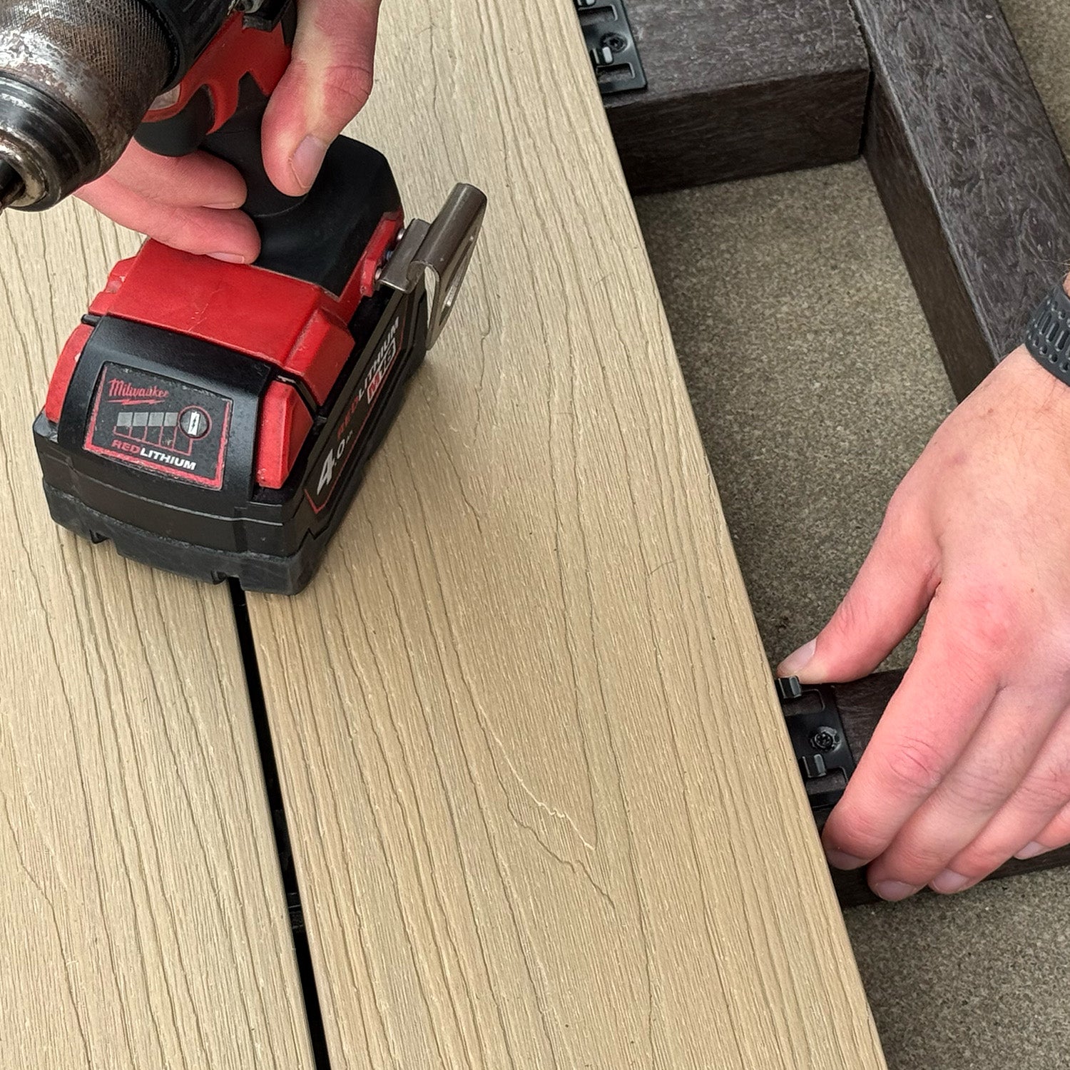 person using a power tool on a composite deck installation