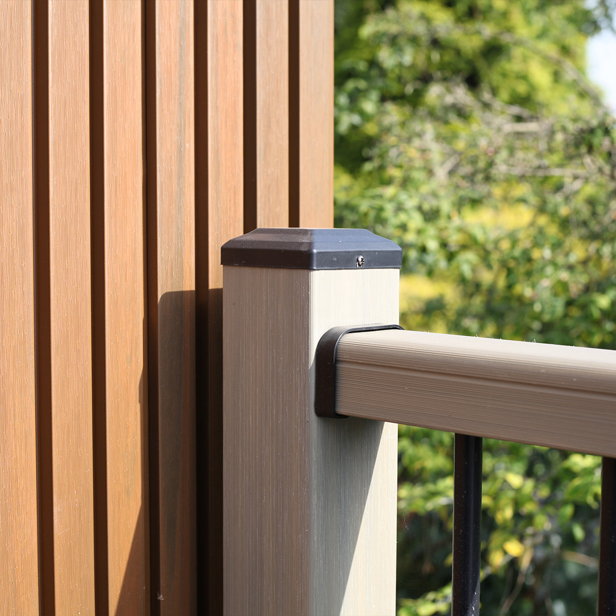 composite railing with post against a blurred green outdoor background