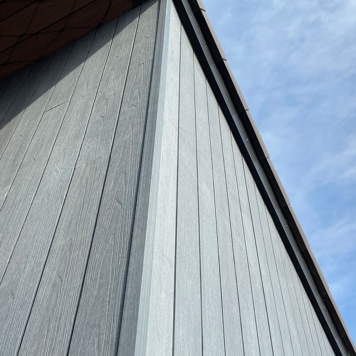 close-up of a building's grey composite facade with a clear blue sky