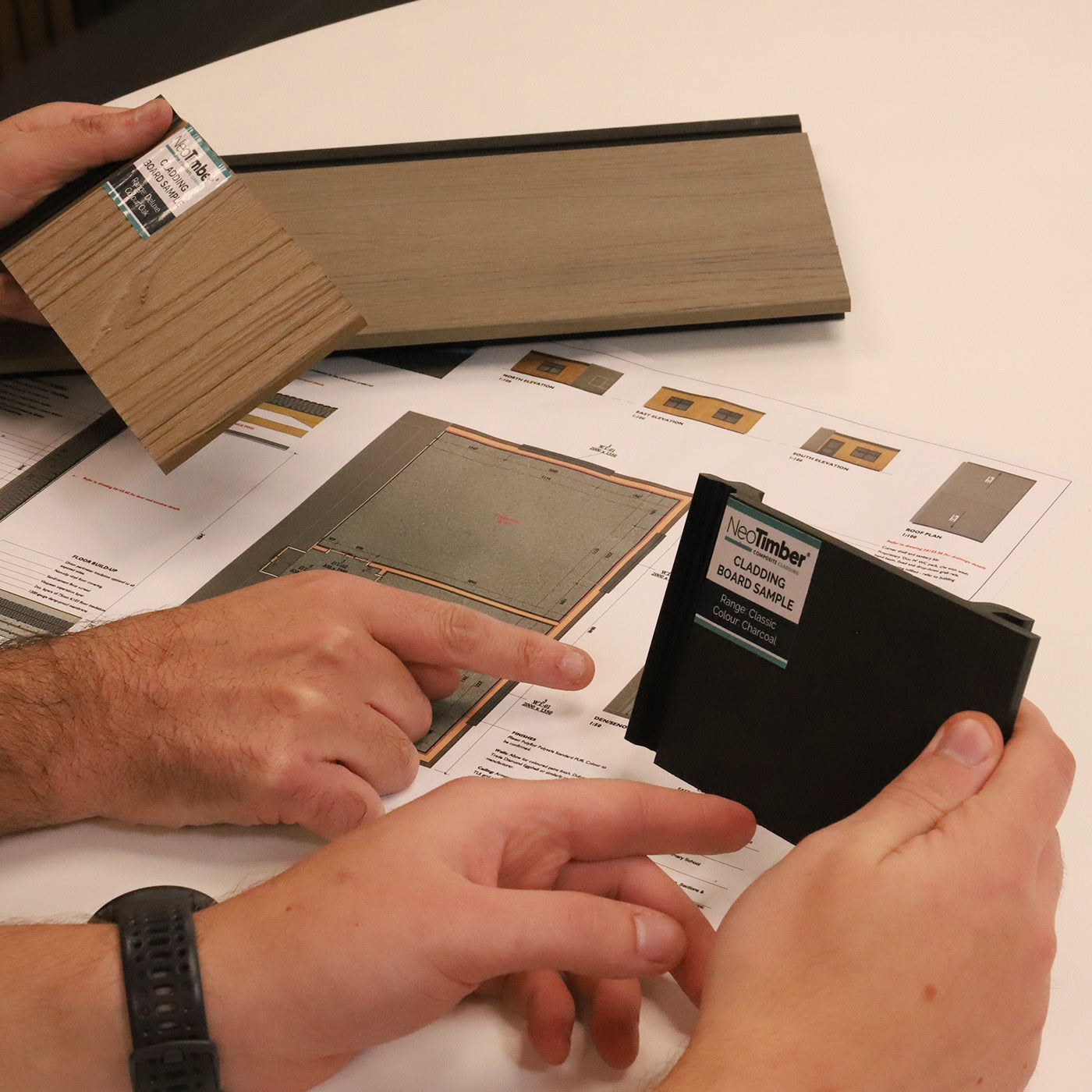 person comparing neotimber composite samples with a sample book on a table