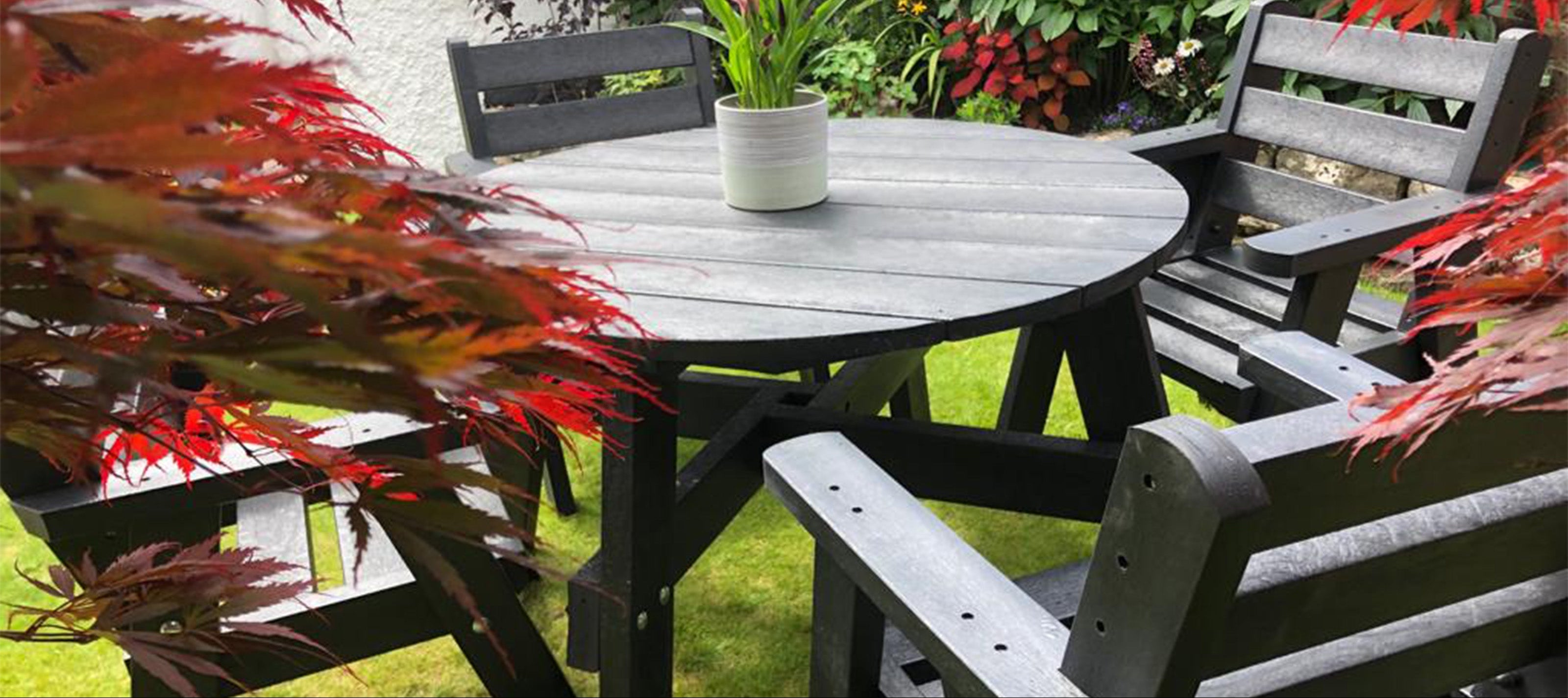 NeoTimber recycled plastic table and chairs with plants and flowers in a garden setting
