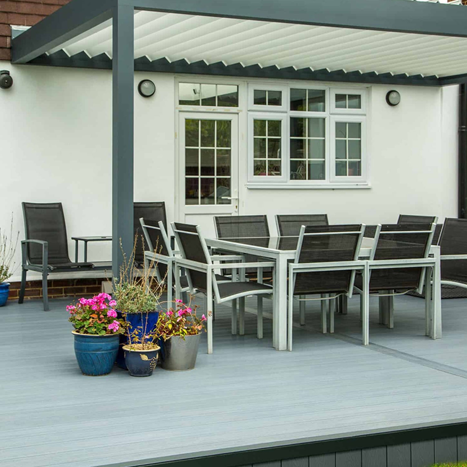 outdoor patio area with dining table and chairs on a composite deck, featuring potted plants