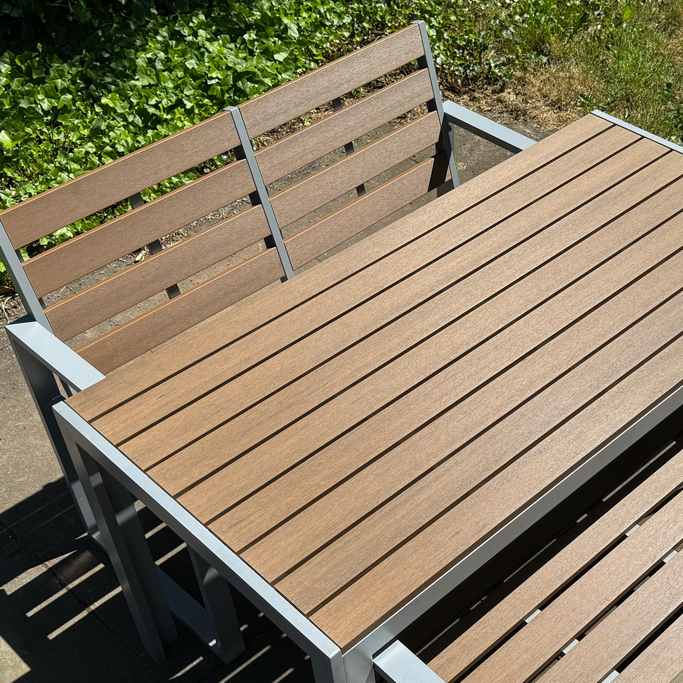 neotimber composite outdoor table and chairs with a green garden background