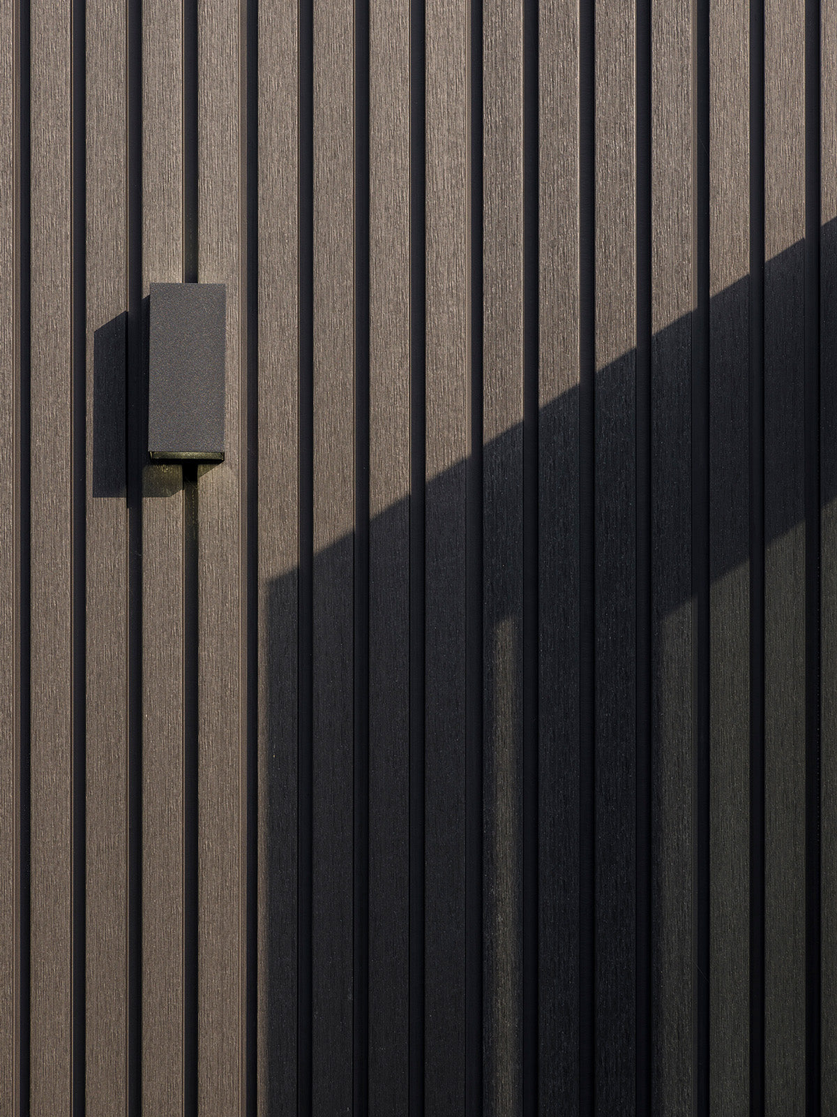 close-up of a slatted composite cladding wall with horizontal slats and a square light fixture