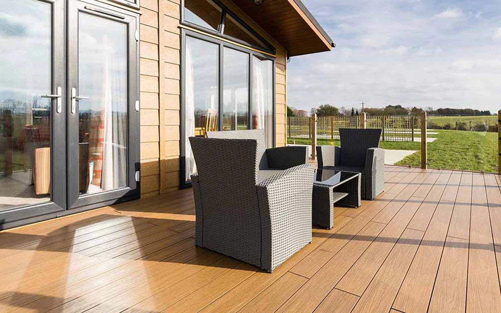 NeoTimber® Composite deck with outdoor furniture and a view of a lodge and garden.