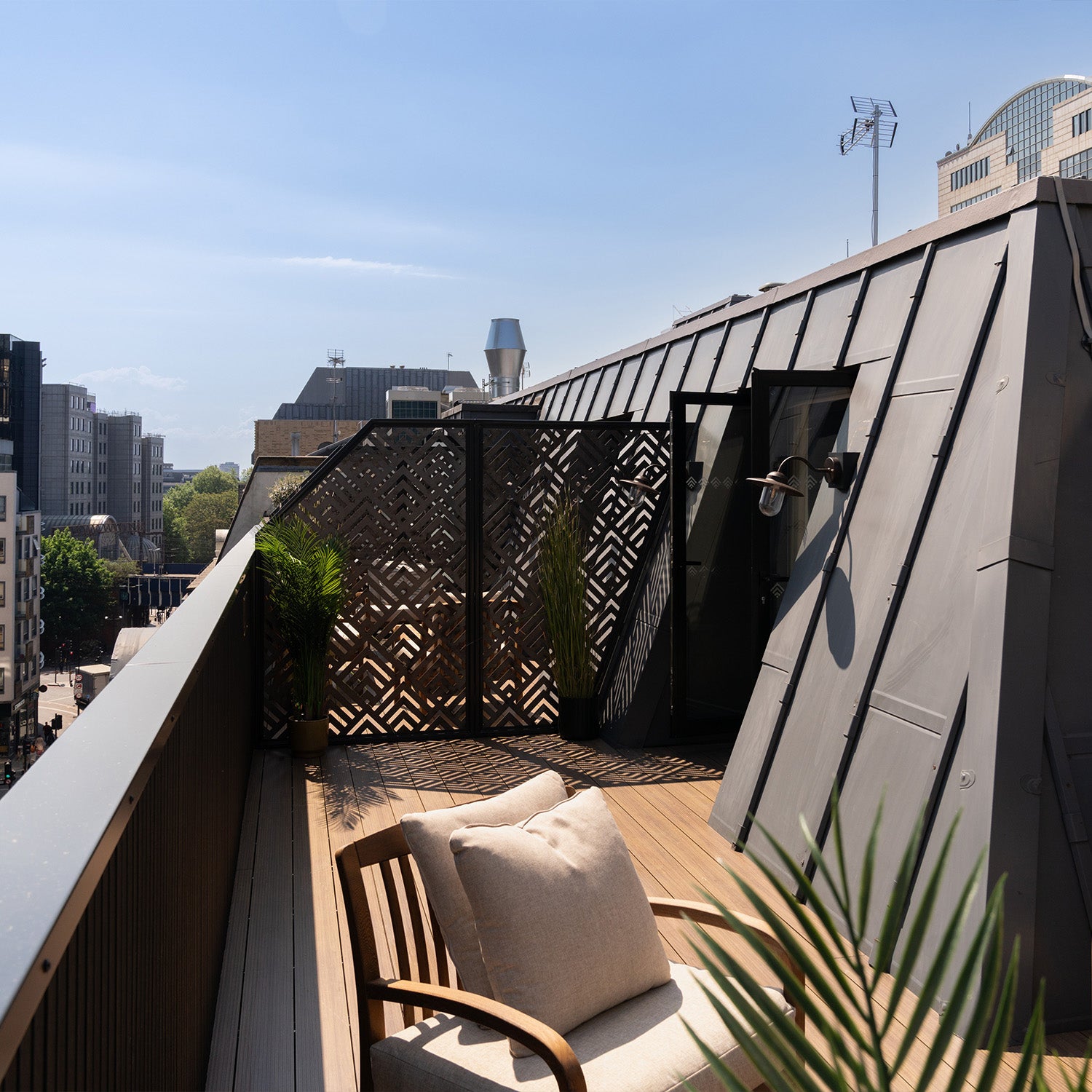 rooftop aluminium decking patio with wooden chair, cushions, decorative accessories, and city skyline views