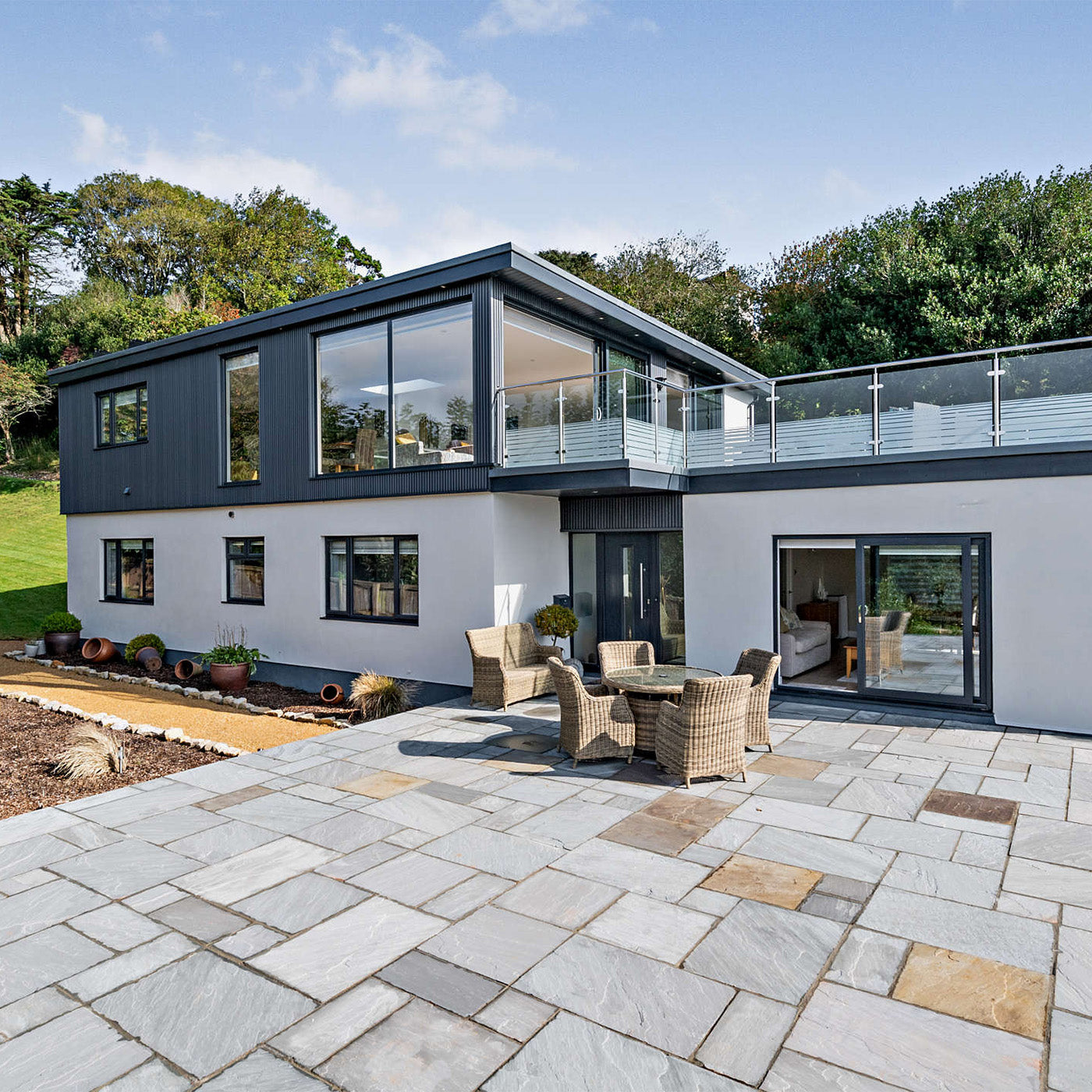 modern two-storey home with grey composite cladding and large paved patio showcasing trade project results
