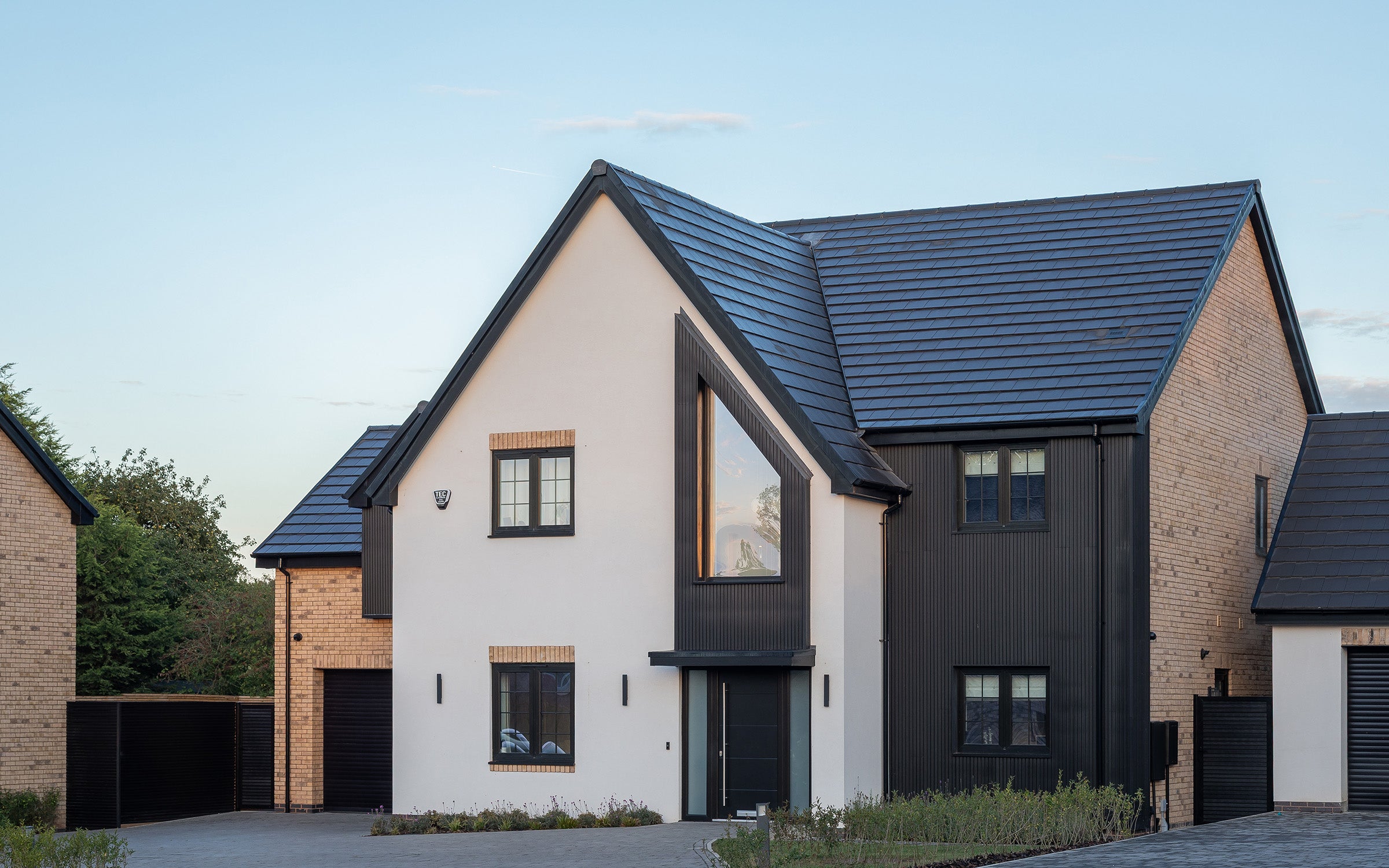 modern house with beige, black, and brick exterior featuring composite cladding