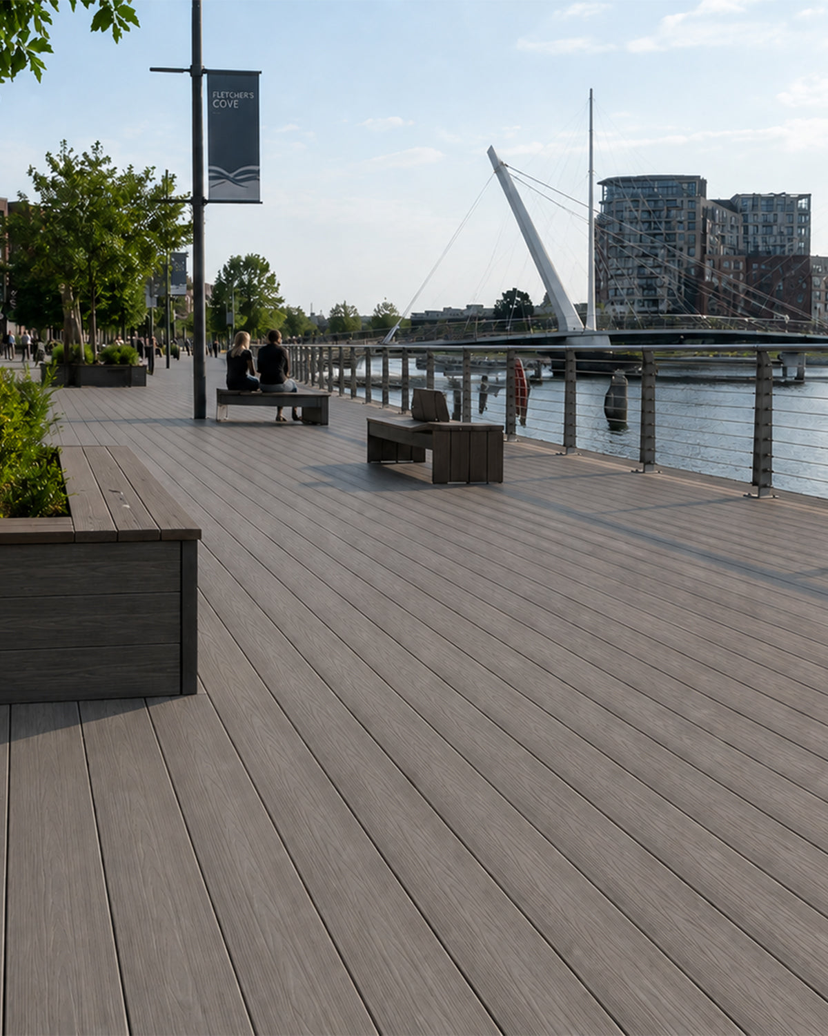 NeoTimber® composite deck by a waterfront with people sitting and a bridge in the background