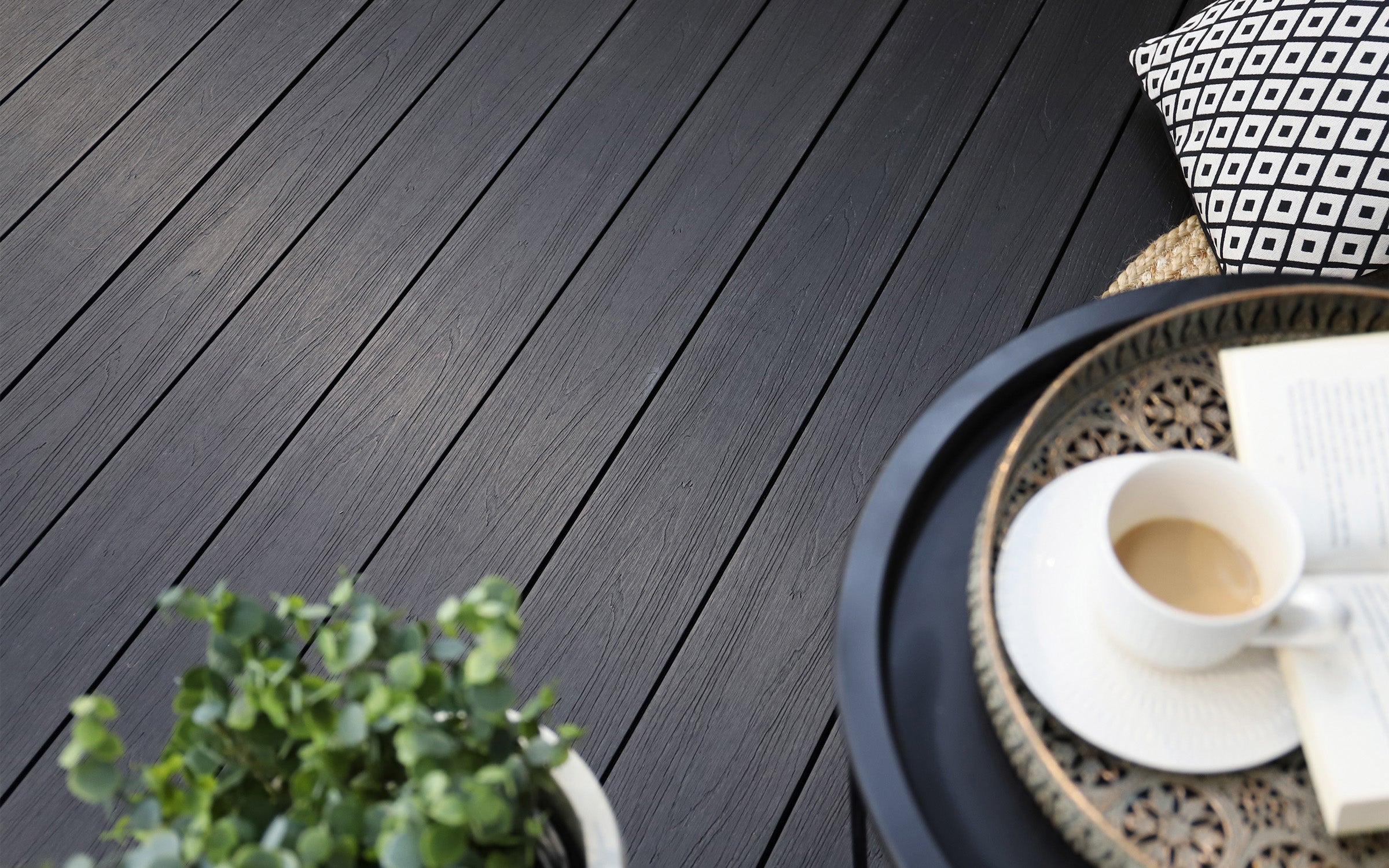 dark charcoal black composite deck with a plant, coffee cup, and decorative items on a table
