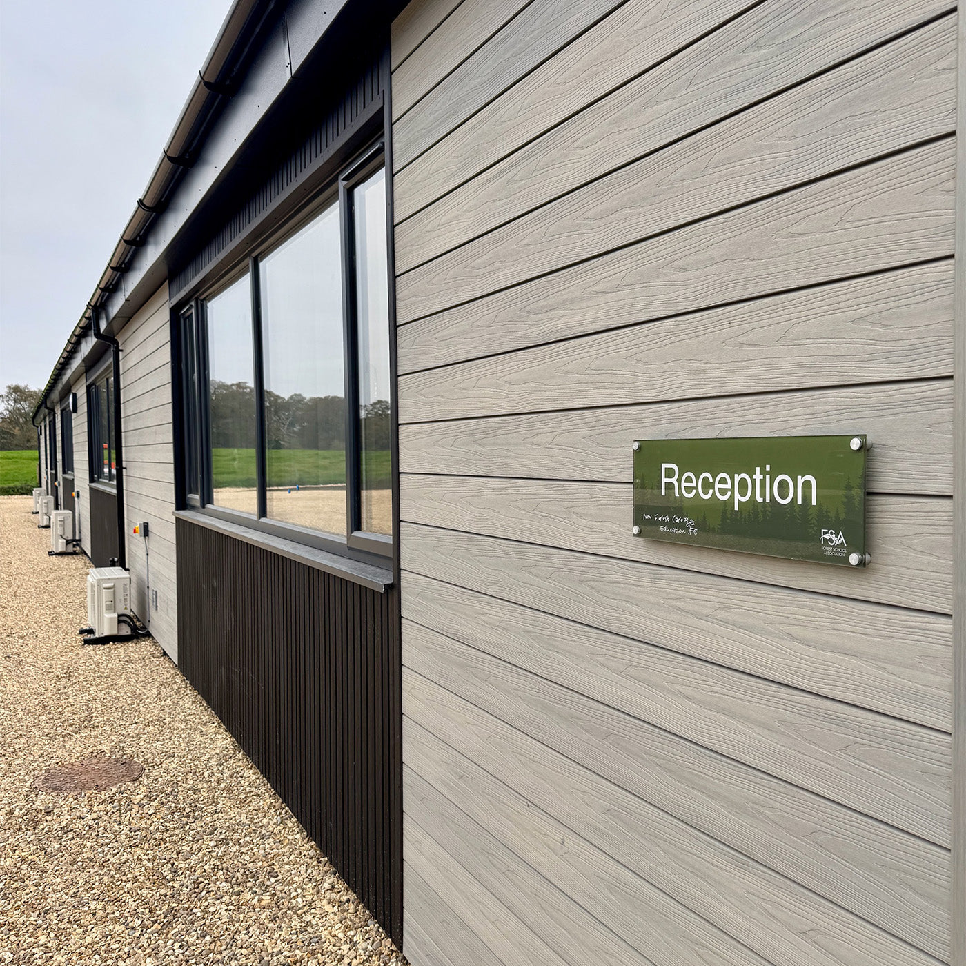 building exterior with 'Reception' sign on a composite cladding wall