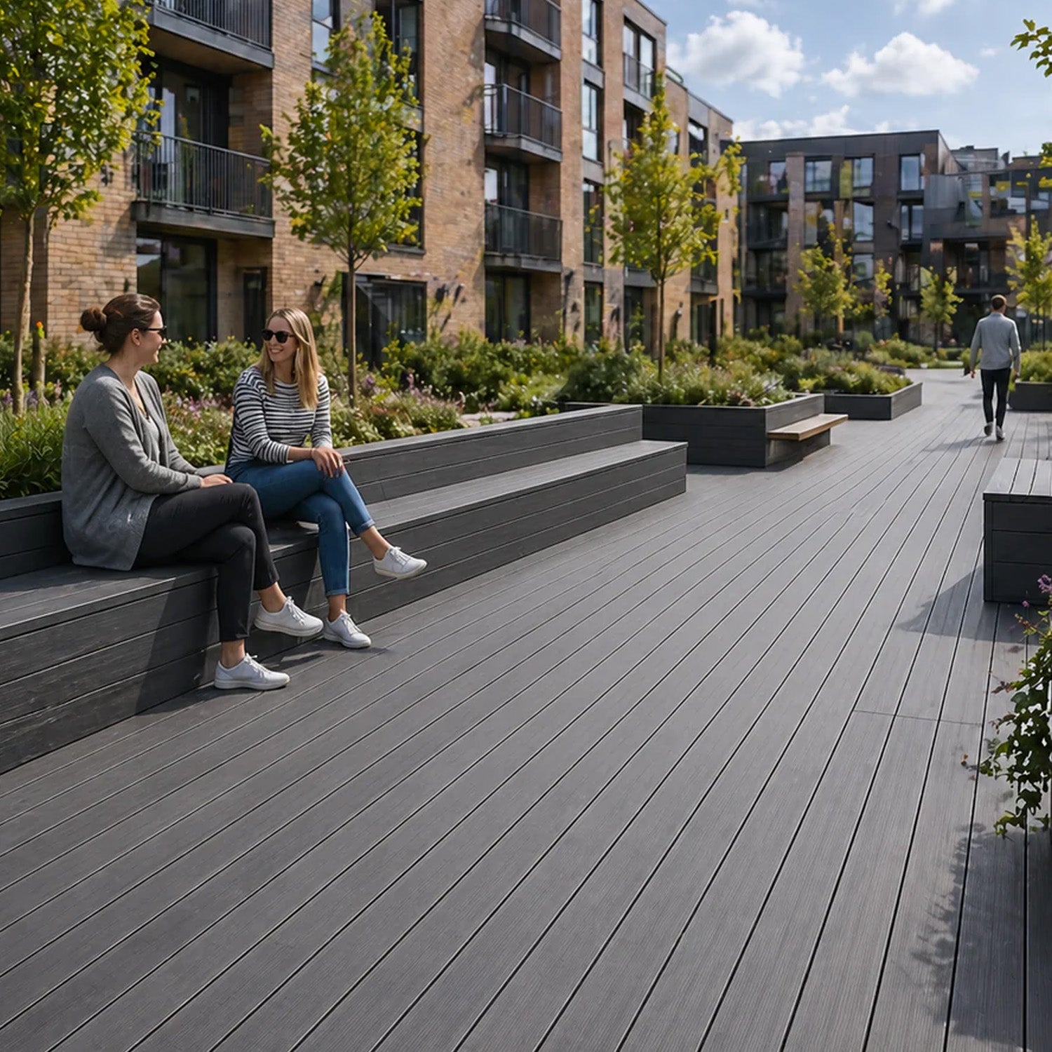 two women sitting on a neotimber composite bench in an urban setting with apartment buildings in the background