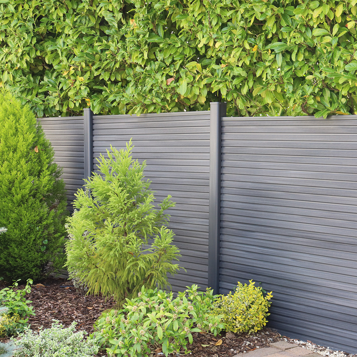 grey composite fence panels with green shrubs and plants in front