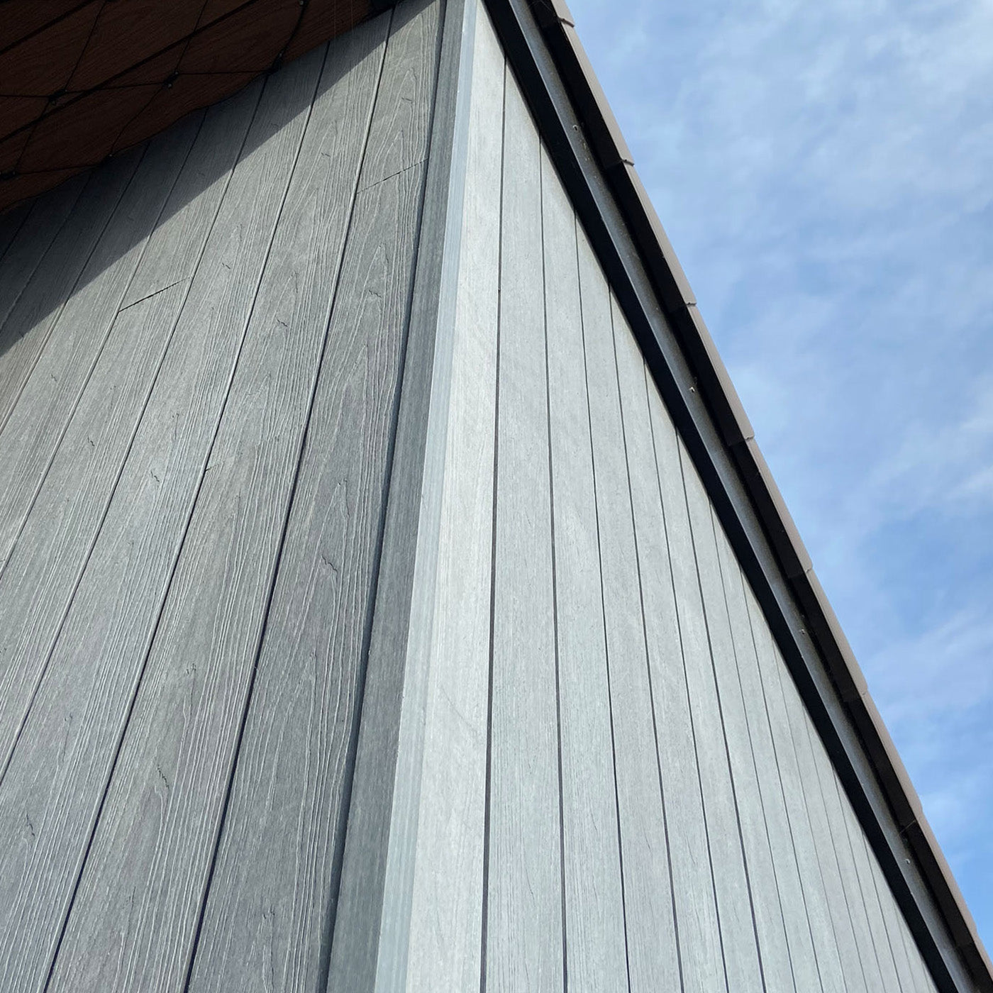 close-up of a building's grey composite siding with a clear blue sky background