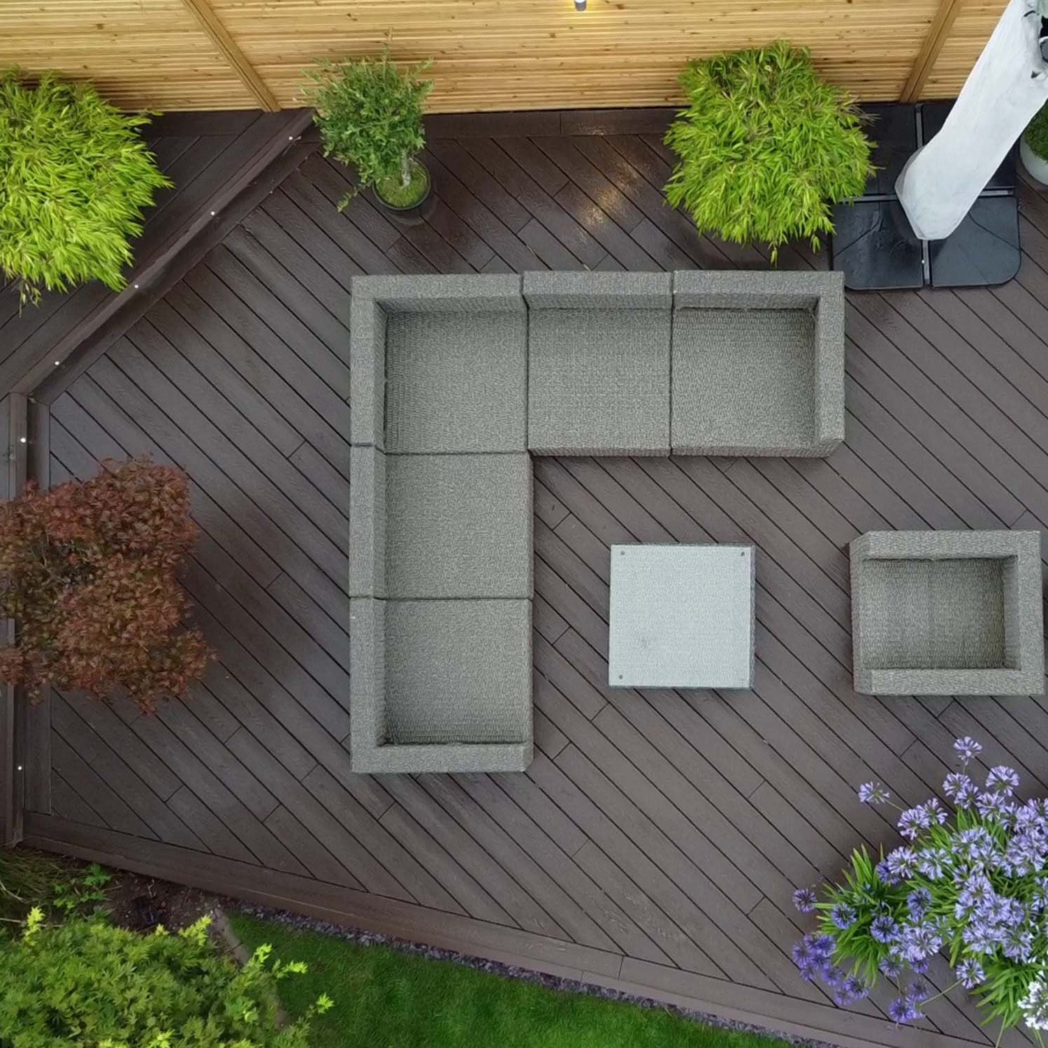 outdoor patio with grey sectional sofa, potted plants, and flowers on a neotimber composite deck