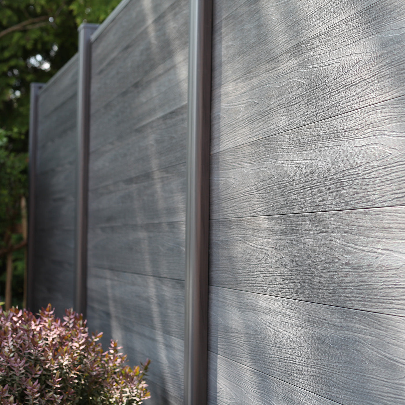 woodgrain textured grey composite fencing with a plant in the foreground